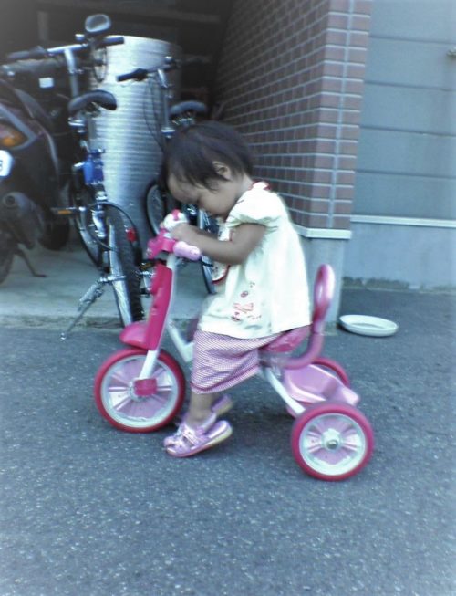 三輪車にまたがる脳性まひ児